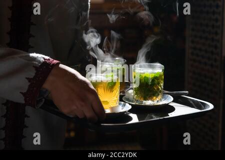 Traditioneller Minztee in Gläsern, die von der Sonne beleuchtet dampfen Serviert auf Tablett Stockfoto
