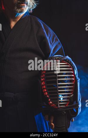 Cropped Foto von reifen Mann hält Kendo Helm. Spezielles Outfit für den Kampf. japanische Kampfkunst Konzept Stockfoto