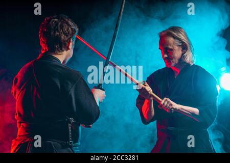Zwei Kendo Kämpfer üben Kenjutsu, japanische Kampfkunst mit Samurai Schwerter. Menschen kämpfen Stockfoto