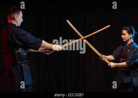 Zwei Kendo-Kämpfer einander gegenüberliegend mit Shinai über dunklen Raum isoliert. Japanische Kampfkunst der Schwertkampf. kendo Konzept Stockfoto