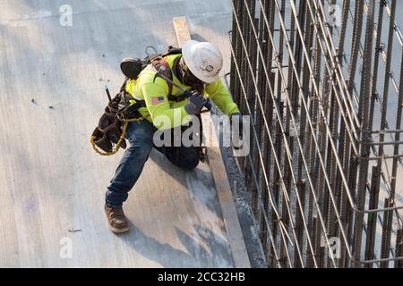 Bauarbeiter, die Sicherheitsausrüstung und Gesichtsschutz tragen, verwendet auf der Baustelle in der Parkgarage in der Nähe der Innenstadt von Austin, Texas, ein Stativ-montiertes Transportmittel. Stockfoto