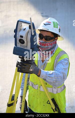 Bauarbeiter, die Sicherheitsausrüstung und Gesichtsschutz tragen, verwendet auf der Baustelle in der Parkgarage in der Nähe der Innenstadt von Austin, Texas, ein Stativ-montiertes Transportmittel. Stockfoto