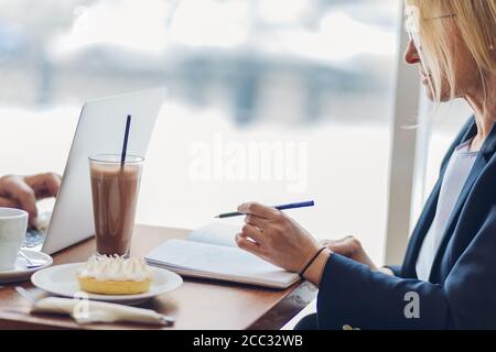 Blonde Frau arbeitet während der Mittagspause. Nahaufnahme abgeschnitten Seitenansicht Foto. Stockfoto