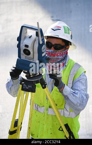 Bauarbeiter, die Sicherheitsausrüstung und Gesichtsschutz tragen, verwendet auf der Baustelle in der Parkgarage in der Nähe der Innenstadt von Austin, Texas, ein Stativ-montiertes Transportmittel. Stockfoto