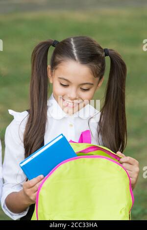 Schulmädchen Putting Buch im Rucksack, bereit für den Unterricht Konzept. Stockfoto