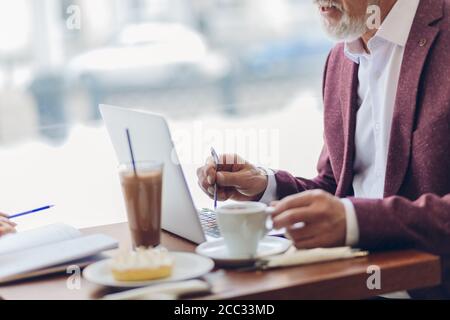 Handsome stilvolle Senior Geschäftsmann mit Kaffee und dabei seine Arbeit in Cafe.close up Seitenansicht abgeschnitten Foto. Job, Beruf Stockfoto