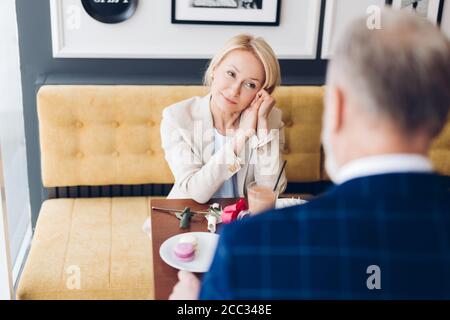 Angenehm lächelnde Frau verbringen Zeit mit ihrem Mann in der Cafe nach dem Arbeitstag Stockfoto