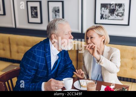 Reifes Paar mit Spaß im Café. Close up photo.Entertainment wunderschöne blonde Frau kümmert sich um ihren Mann Stockfoto