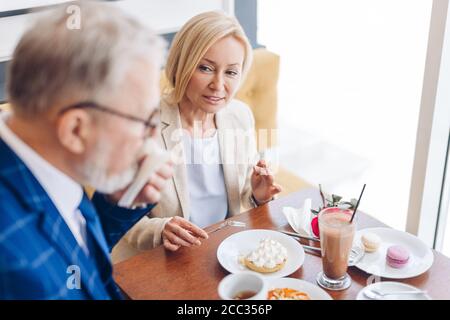 Angenehme gut aussehende Frau, die den Mann, der seinen Mund mit einer Papierserviette abwischt. Nahaufnahme Foto Stockfoto
