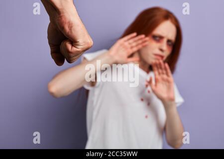 Konzentrieren Sie sich auf geballte Männerfaust. Frau schützt sich vor grausamen Wahnsinnigen. Verschwommener Hintergrund, Studioaufnahme Stockfoto