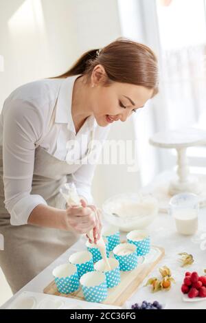Attraktive lächelnde Mädchen schaffen leckere Leckereien für jeden Anlass, close up Seite Ansicht photo.Cupcake Rezept Stockfoto