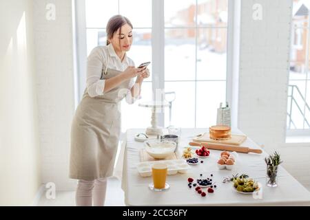 Attraktive Mädchen, das Bild von Zutaten für Kuchen. Close up Foto. Angenehmes Mädchen Senden von Fotos an ihre Freunde während der Arbeit in der Küche. Kopieren Stockfoto