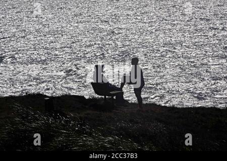 Zwei Personen sitzen auf einer Bank, während sie auf einem Blick über den Pazifik in Yachats, Oregon, entlang der Pazifikküste von Oregon reden. Stockfoto