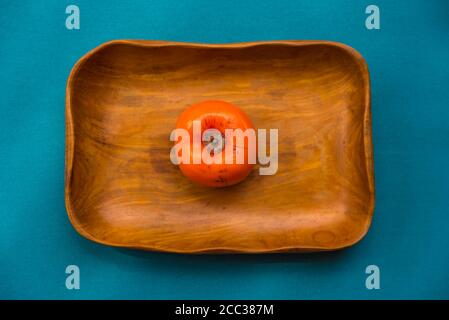 Draufsicht auf Kaki-Früchte in einer Holzschüssel und blauem Hintergrund. Stockfoto