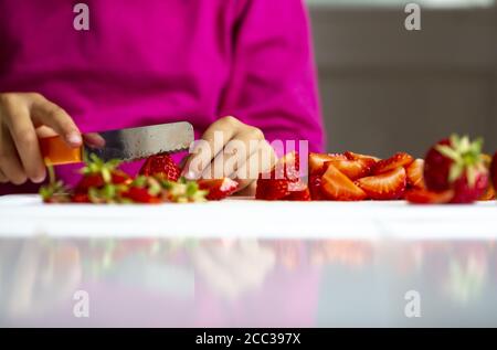 Mädchen (8) schneidet Erdbeeren, Kiel, Schleswig-Holstein, Deutschland Stockfoto