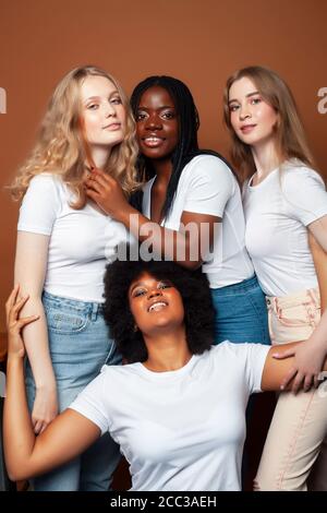 Junge hübsche kaukasische, afro, skandinavische Frau posiert fröhlich zusammen auf braunem Hintergrund, Lifestyle diverse Nationalität Menschen Konzept Stockfoto