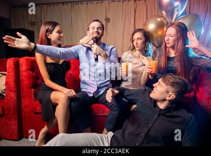 Junge Brandstifter kaukasischen Menschen versammelten sich in Karaoke-Bar zu singen und Spaß zu haben, feiern, emotionale Gruppe von jungen Jungs und Damen Stockfoto