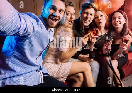 Gruppe von trendigen jungen Sängern haben Spaß zusammen in Karaoke-Bar, modische und positive Jungs und Damen feiern, singen. Positive Zeitvertreib Stockfoto