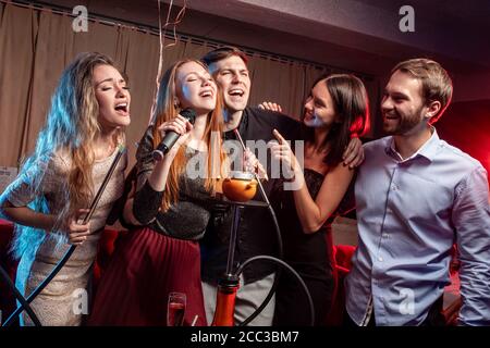 Junge Frauen und Männer Clubber verbringen Zeit in Karaoke-Bar, haben Spaß singen im Mikrofon. Freizeit, Feier, Party-Konzept Stockfoto