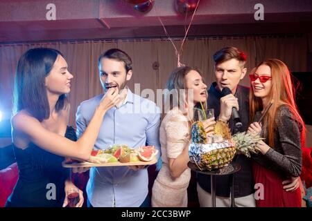 Junge Brandstifter kaukasischen Menschen versammelten sich in Karaoke-Bar zu singen und Spaß zu haben, feiern, emotionale Gruppe von jungen Jungs und Damen Stockfoto