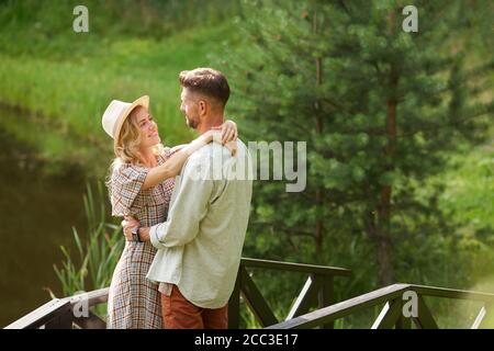 Seitenansicht Porträt von romantischen erwachsenen Paar umarmen und einander beim Stehen am See im Freien in rustikalen Landschaft, kopieren Raum Stockfoto