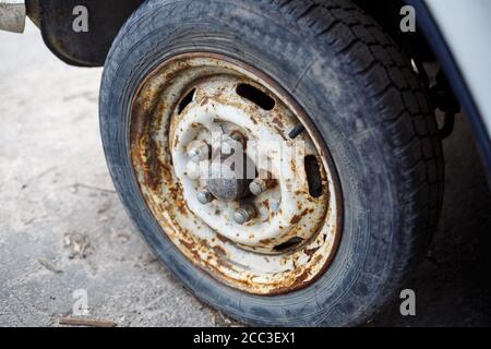 Rostiges Rad mit einem Reifen aus einem Auto. Verlassene Autoreifen. Stockfoto