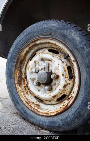 Rostiges Rad mit einem Reifen aus einem Auto. Verlassene Autoreifen. Stockfoto