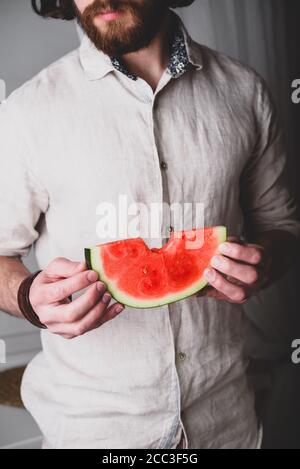 Bärtiger Mann hält in den Händen gebissen aus Scheibe Wassermelone Stockfoto