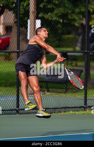 MD, USA 08/14/2020: Ein sportlicher hispanic-Mann mit schweißtreibendem ärmellosen Hemd und Shorts nimmt während eines Tennisspiels auf einem lokalen Tennisplatz in Ba eine Aufschrift auf Stockfoto