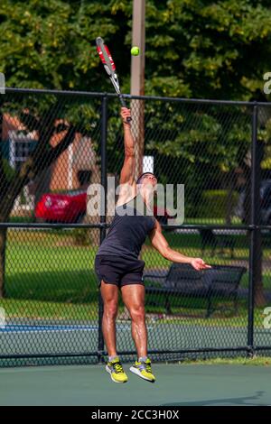 MD, USA 08/14/2020: Ein sportlicher hispanic-Mann mit schweißtreibendem ärmellosen Hemd und Shorts nimmt während eines Tennisspiels auf einem lokalen Tennisplatz in Ba eine Aufschrift auf Stockfoto