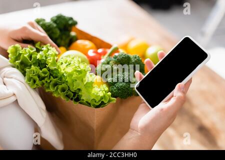 Selektiver Fokus der Frau hält Smartphone mit leerem Bildschirm in der Nähe Lebensmittel Stockfoto