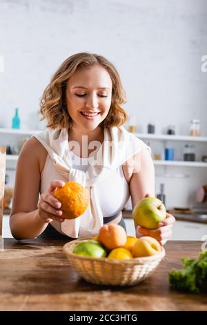 Selektiver Fokus der Frau, die Orange und Apfel in den Händen hält Stockfoto