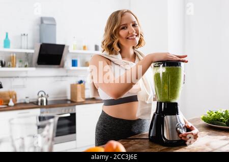 Selektiver Fokus der jungen Frau, die grünen Smoothie im Mixer mischt Stockfoto