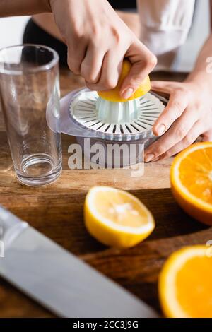Beschnittene Ansicht einer jungen Frau, die die Hälfte der Orange einquetscht Entsafter Stockfoto