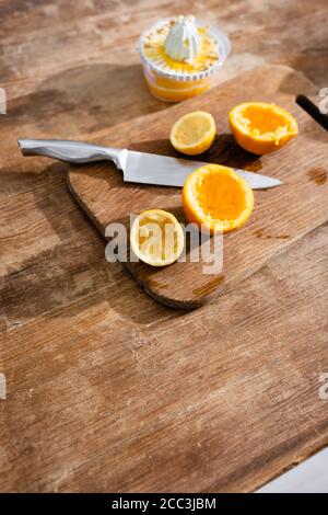 Hohe Winkelansicht der gequetschten orangen Hälften in der Nähe von Messer und Entsafter Stockfoto