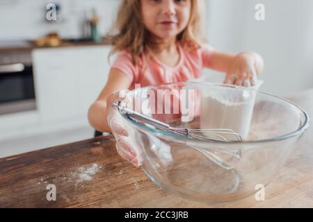Selektiver Fokus von Kid Mischen Mehl in Messkrug in der Nähe Beim Kochen auf dem Küchentisch in einer Glasschüssel verquirlen Stockfoto