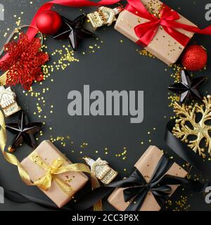 Luxuriöser Weihnachtsrahmen aus Geschenkschachteln, festliche Dekorationen, Satinband auf schwarzem Tisch. Weihnachten, glückliches neues Jahr Hintergrund. Flach liegend, Kopierer Stockfoto