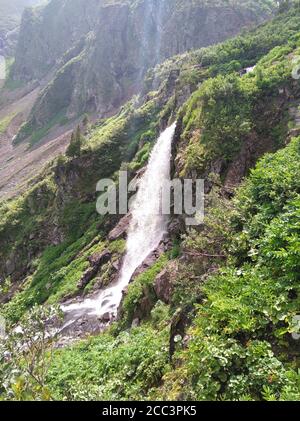 Ein kleiner, stürmischer Wasserfall, der von steilen Klippen in ein von Bergen umgebenes Tal herabfließt. Ivanovskie Seen, Chakassien, Südsibirien, Russland. Stockfoto