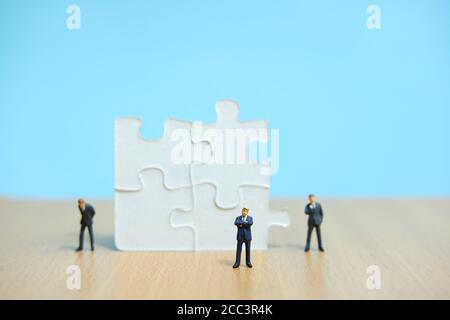 Business-Strategie konzeptuelles Foto - Gruppe von Miniatur-Geschäftsmann stehend Auf Holztisch vor dem fehlenden Puzzleteil Stockfoto