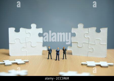 Business-Strategie konzeptuelles Foto - Gruppe von Miniatur-Geschäftsmann stehend Auf Holztisch vor dem fehlenden Puzzleteil Stockfoto