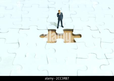 Business-Strategie konzeptuelles Foto - Miniatur Geschäftsmann denken vor Des fehlenden Puzzles Stockfoto