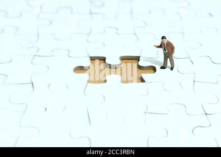 Business-Strategie konzeptionelle Foto - Miniatur Geschäftsmann zeigt auf fehlende Puzzleteil Stockfoto