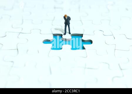 Business-Strategie konzeptionelle Foto - Miniatur Geschäftsmann Blick auf Fehlende Puzzleteile Stockfoto