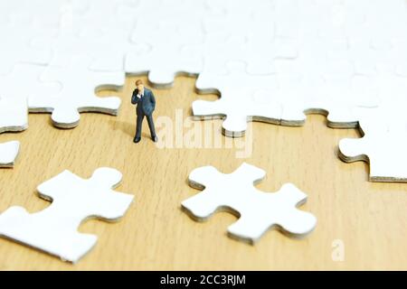Business-Strategie konzeptionelle Foto - Miniatur Geschäftsmann denken vor Von Puzzle Stockfoto