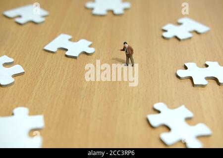 Business-Strategie konzeptionelle Foto - Miniatur Geschäftsmann zeigt auf fehlende Puzzleteil Stockfoto
