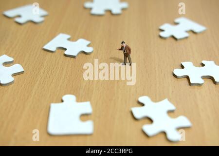 Business-Strategie konzeptionelle Foto - Miniatur Geschäftsmann zeigt auf fehlende Puzzleteil Stockfoto