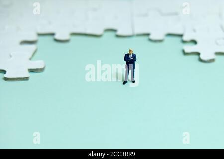 Business-Strategie konzeptionelles Foto - Miniatur Geschäftsmann vor stehen Puzzle-Puzzle Stockfoto