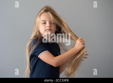 Reilly Stancombe, bevor er seinen ersten Haarschnitt bei Masters & Misters Barbers in Clacton-on-Sea, Essex, machte, um Geld für den Little Princess Trust zu sammeln. Der neunjährige Reilly aus Little Clacton, Essex, der noch nie einen Haarschnitt bekommen hat, spendet seine langen Haare, um sie zu Perücken für krebskranke Kinder zu machen. Stockfoto