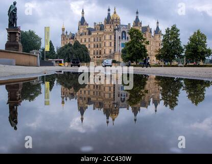 18. August 2020, Mecklenburg-Vorpommern, Schwerin: Das Schweriner Schloss spiegelt sich in einer Pfütze wider. Nach Gewittern und Niederschlägen zeigt das Wetter in Norddeutschland seine düstere Seite. Foto: Jens Büttner/dpa-Zentralbild/dpa Stockfoto