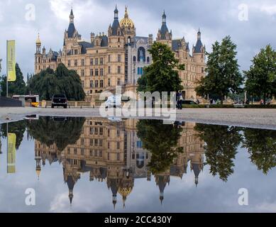 18. August 2020, Mecklenburg-Vorpommern, Schwerin: Das Schweriner Schloss spiegelt sich in einer Pfütze wider. Nach Gewittern und Niederschlägen zeigt das Wetter in Norddeutschland seine düstere Seite. Foto: Jens Büttner/dpa-Zentralbild/dpa Stockfoto